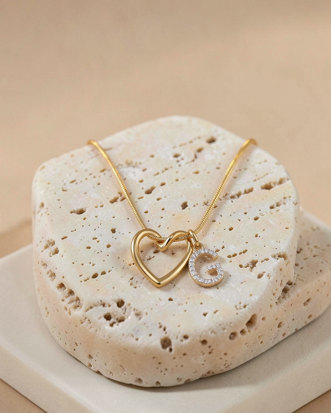The Keepsake Heart necklace draped over travertine stone