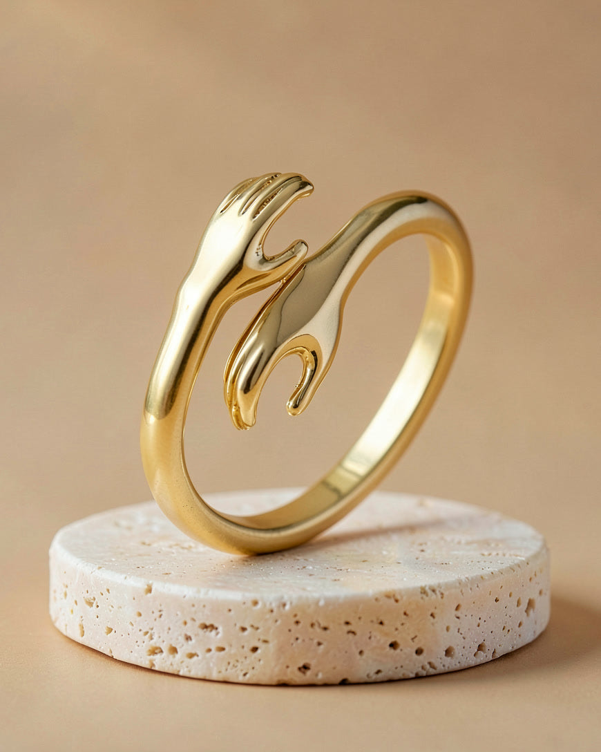 The Hug ring in gold standing on a travertine block
