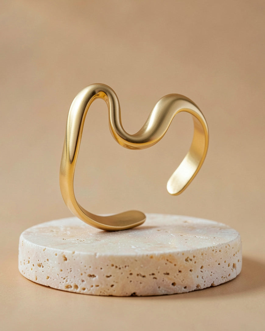 The Serpent ring in gold tone on a travertine block